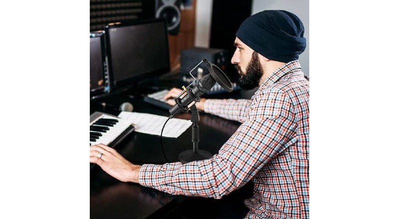 Un hombre usando el micrófono Maono junto con un piano
